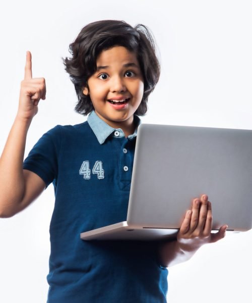 Asian Indian school kid holding and using laptop while standing against white background